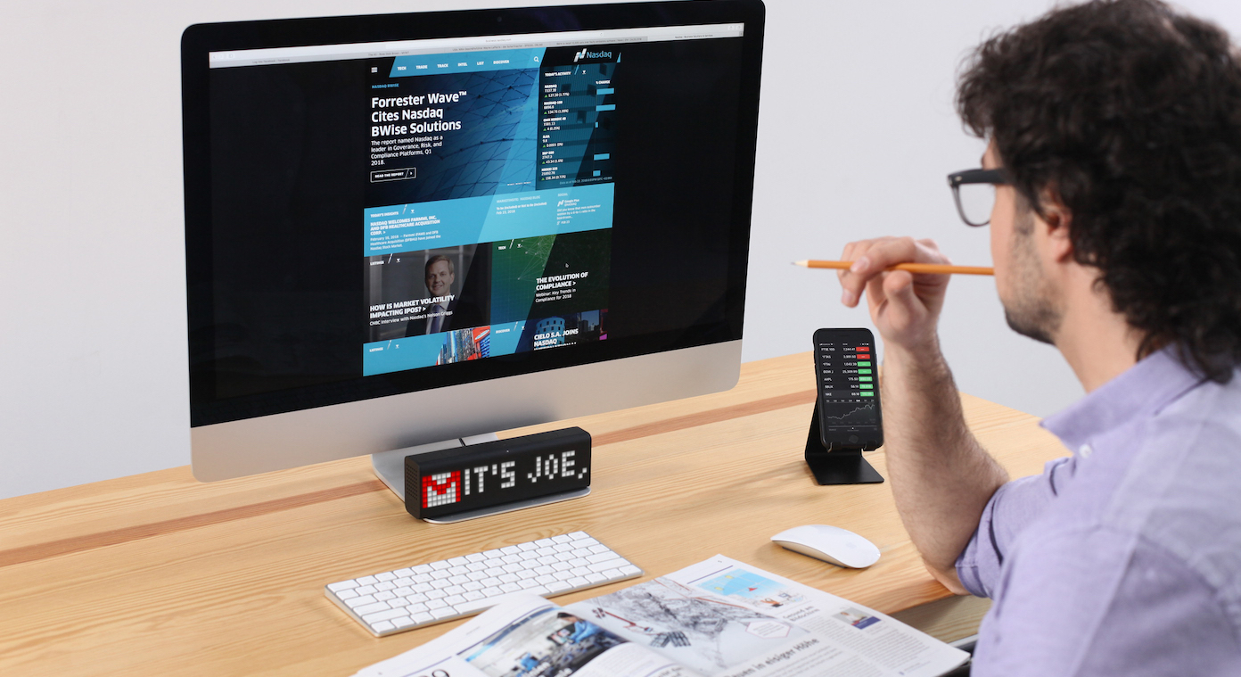 Man is loking at LaMetric Time smart clock device which displays subject of newly received email